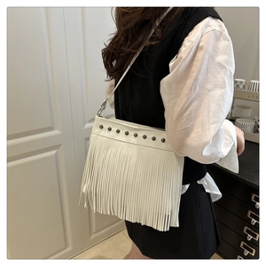 Detalle del bolso bandolera blanco con remaches y flecos largos en una modelo
