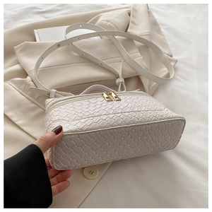 Detail of cream woven box handbag with golden zippers and adjustable strap