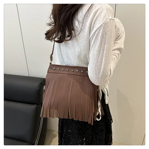 Detalle de bolso marrón con flecos largos y remaches metálicos de estilo vintage