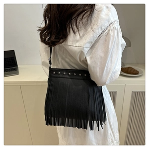 Detalle de bolso de hombro con flecos negros, remaches plateados y piel granulada