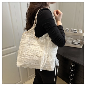 Detail of white lace tote bag featuring an oversized bow and intricate floral patterns
