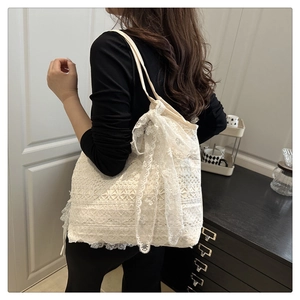Detail of cream lace tote bag with floral textures and large decorative bow accent