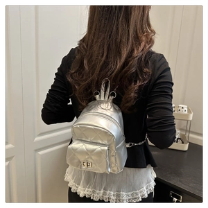 Silver quilted mini backpack with chain strap and metallic finish on female model
