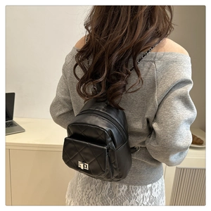 Detail of quilted mini bucket backpack featuring silver twist lock and metal chain strap