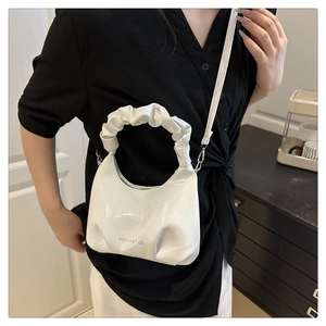 Detail of white pleated handle handbag with fashion text logo on glossy leather finish