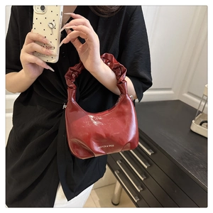 Detail of burgundy ruched handbag featuring fashion print and elegant gathered handle