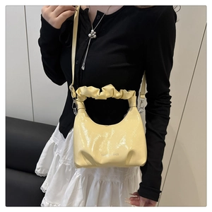 Detail of pale yellow pleated dumpling bag featuring fashion text and adjustable strap