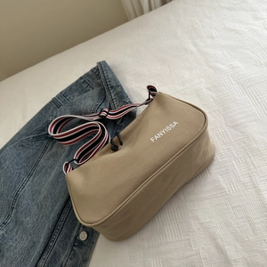 Dettaglio della borsa in tela kaki con logo FANYISSA e tracolla a righe colorate