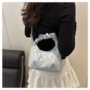 Detail of silver pleated cloud bag featuring ruffle handle and metallic finish texture