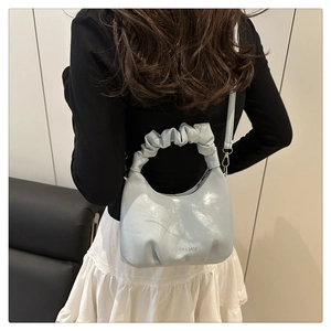 Close-up of ice blue patent leather cloud bag featuring fashion lettering and silver hardware