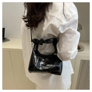 Detail of black glossy bucket bag with cloud-like ruched handle and silver metal hooks