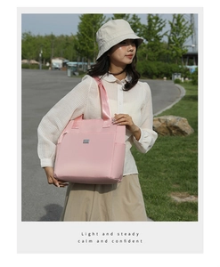Pink oxford tote bag detail featuring square metal logo and wide shoulder strap