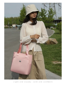 Close-up of pink nylon tote bag showing front zip pocket and reinforced webbing handles