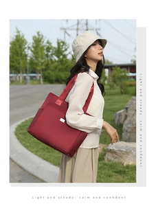 Close-up of wine red nylon tote bag featuring reinforced stitching and side pocket detail