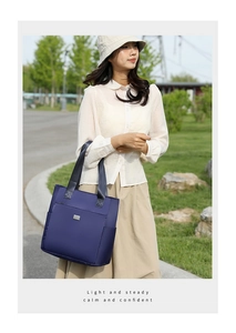 Detail of navy blue nylon tote bag with front zipper pocket and metal logo plaque