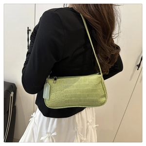 Close-up of light green crocodile embossed baguette bag with long shoulder strap