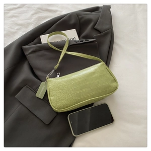 Detailed top view of avocado green crocodile pattern baguette bag with stylish props