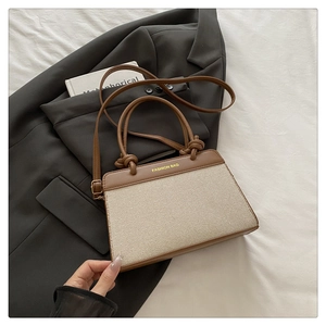 Detail of the chic contrast tote bag with knotted handles on a suit jacket
