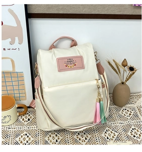 Détail du grand sac à dos crème avec bretelles roses contrastées et pompon coloré