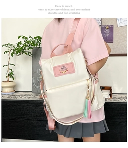 Détail du sac à dos en nylon crème avec bretelles roses et pompon bicolore décoratif