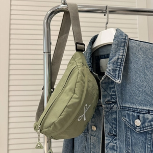 Détail du sac en nylon vert olive avec broderie blanche et bandoulière grise