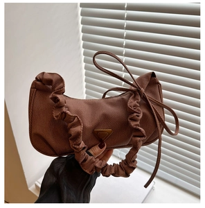 Detail of brown pleated hobo bag with smooth nylon texture and metal triangle logo plaque