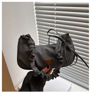 Detail of dark grey textured crossbody bag with ruched handle and golden triangle plaque