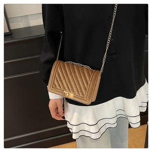 Détail du sac en velours marron matelassé avec bandoulière chaîne et fermoir doré