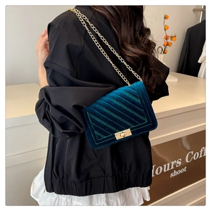 Détail du sac en velours vert avec matelassage chevron et fermoir rotatif doré