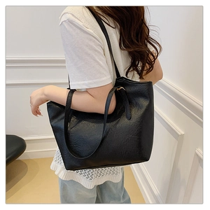 Detailed view of black oversized tote bag showing wrinkled faux leather texture and straps
