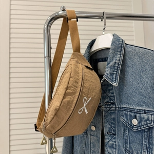 Détail du sac banane en nylon kaki avec broderie croisée blanche et fermeture éclair en métal