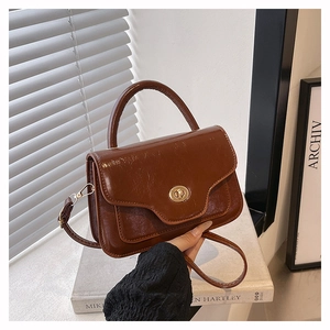 Detail of vintage brown oil wax leather saddle bag with metal clasp and sleek handle