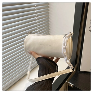 Détail du sac cylindre blanc avec une grosse chaîne en résine et une bandoulière en cuir