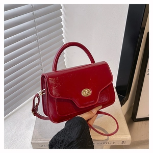 Detail of red patent leather saddle bag with wavy flap and golden twist lock closure