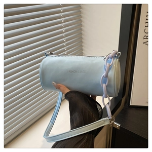 Détail du sac cylindrique bleu clair avec fermeture éclair argentée et chaîne violette