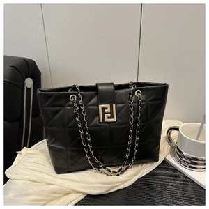 Close-up of black quilted tote bag featuring a gold buckle and metal chain strap