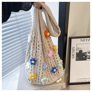 Detailed macro of hand-knitted tote bag with colorful 3D floral accents and mesh texture