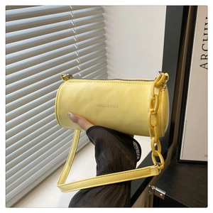 Détail du sac cylindrique jaune clair avec chaîne en résine et texture en cuir PU