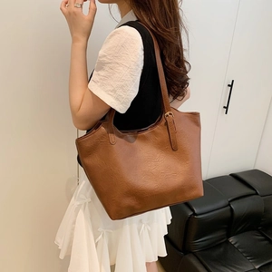 Brown faux leather tote bag with adjustable long straps in a modern interior setting