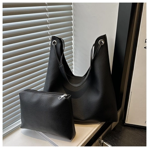 Détail du sac cabas en cuir grainé noir avec œillets métalliques et pochette assortie