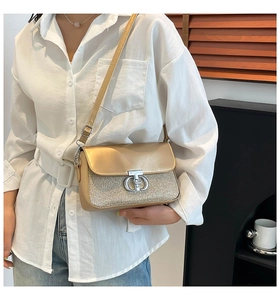 Détail du sac à bandoulière doré champagne avec texture pailletée et fermoir rotatif argenté