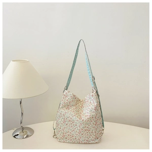 Close-up of floral canvas shoulder bag with blue checkered strap on a white table