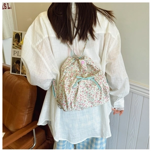 Détail d'un sac à dos à fleurs avec nœud à carreaux bleus et fermoir à bouton rose