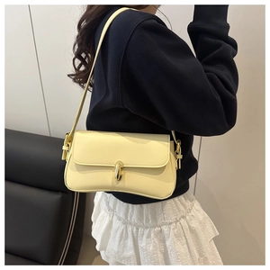 Détail du sac baguette en cuir jaune pâle montrant le fermoir doré sur la bandoulière