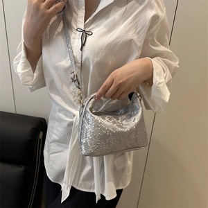 Silver snakeskin bucket bag with gold hardware shown as a crossbody in a minimalist setting