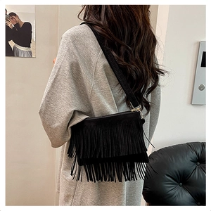 Détail du sac bandoulière bohème en daim noir avec longues franges et boucles dorées