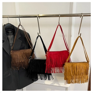 Row of four tassel crossbody bags in brown, black, red and yellow hanging on a metal rack
