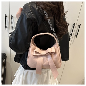 Détail du sac à main rose avec nœud et chaîne argentée porté à l'épaule