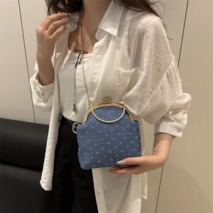 Blue denim crossbody bag with white floral embroidery and vintage gold metal frame