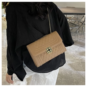 Λεπτομέρεια καφέ καπιτονέ τσάντας με χρυσή τετράγωνη κλειδαριά και λουράκι αλυσίδας